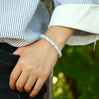 Bracelet tissé bi-colore bleu clair et blanc style mixte porté au poignet.
