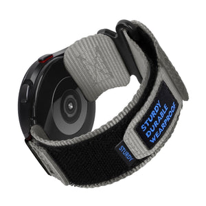 Bracelet en nylon gris avec fermoir velcro noir et étiquette bleue pour Samsung Galaxy Watch.