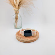 Bracelet Apple Watch en nylon beige avec rayures pastel, fermeture velcro, style sport élégant.