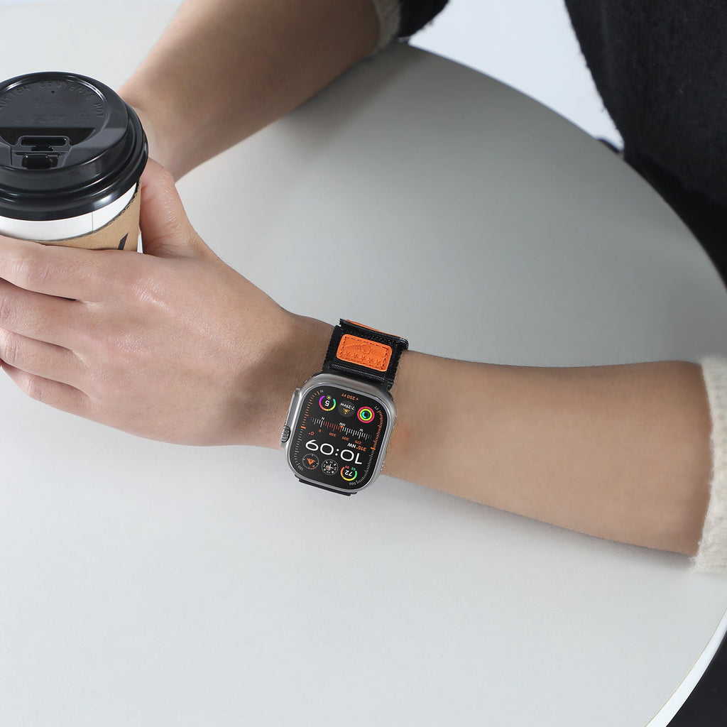 Bracelet Apple Watch en nylon noir et orange, drapeau américain, ajustable, modèle Vino, porté au poignet.