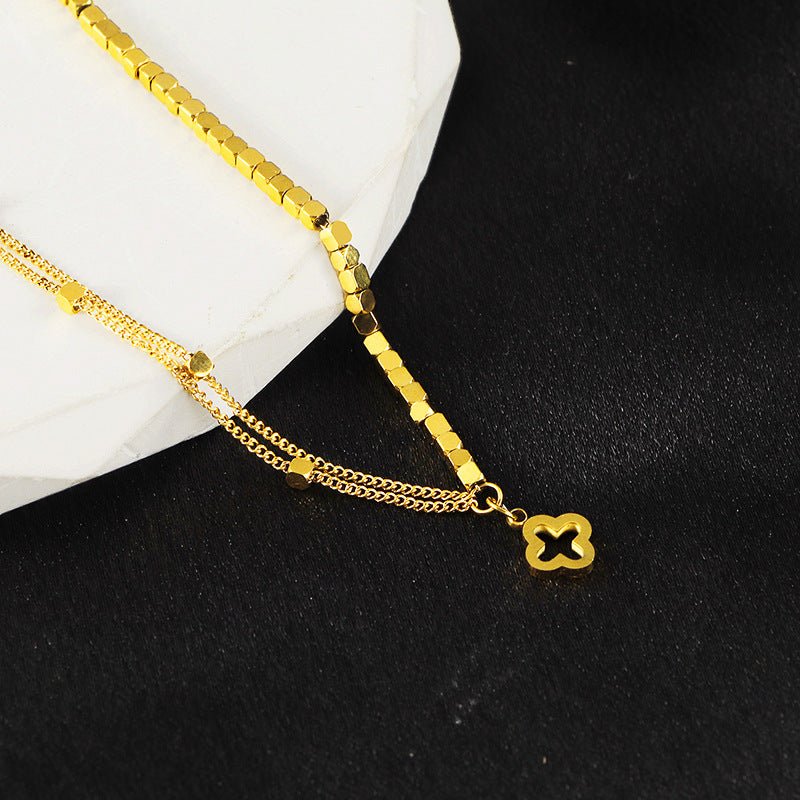 Bracelet en titane doré double chaîne fine avec pendentif trèfle noir bordé d’or, élégant et raffiné.