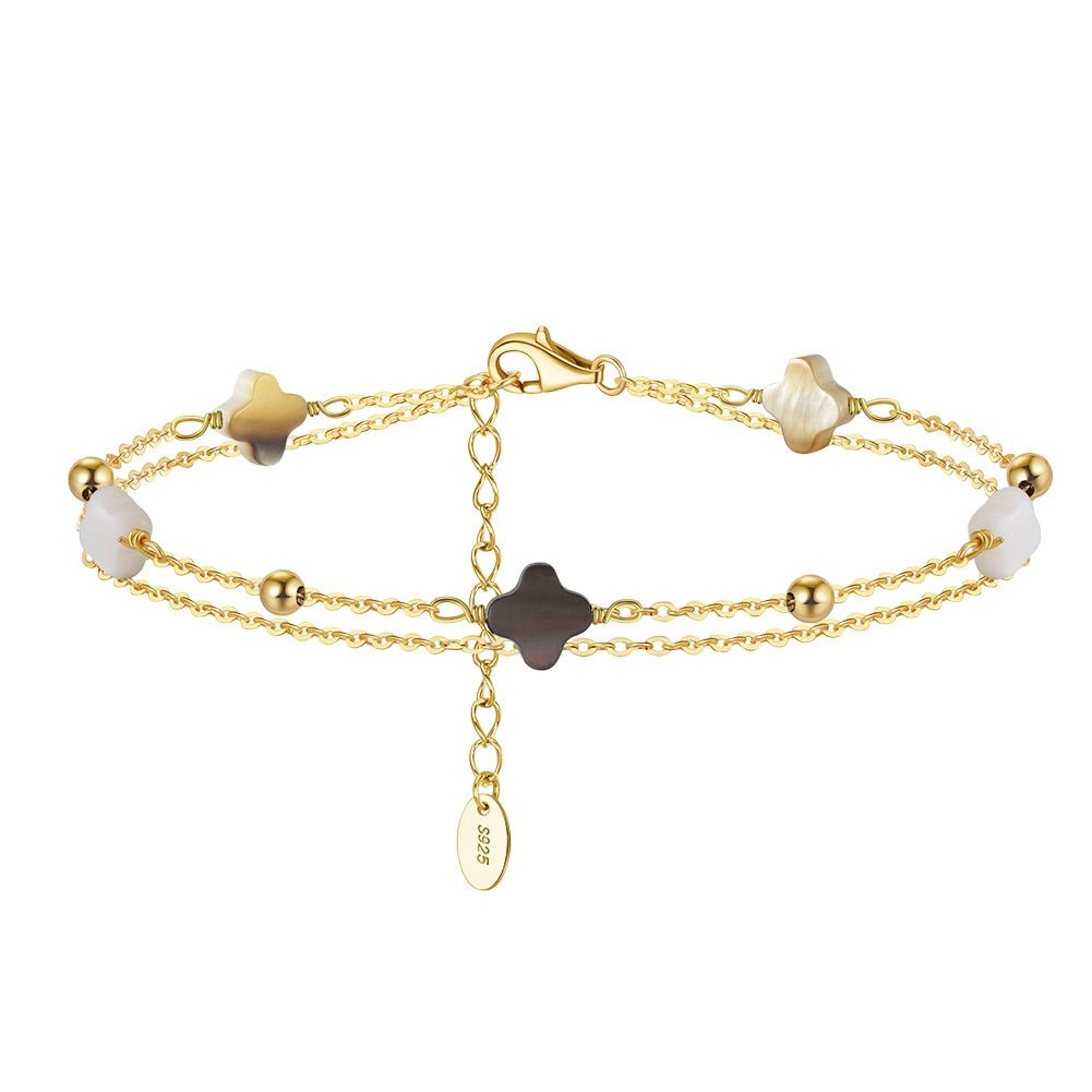 Bracelet double chaîne dorée avec cinq trèfles en nacre blanche, ivoire et noire, perles dorées espacées.