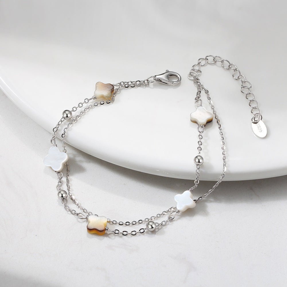 Bracelet double chaîne en argent 925 avec quatre trèfles en nacre blanche et noire délicate.