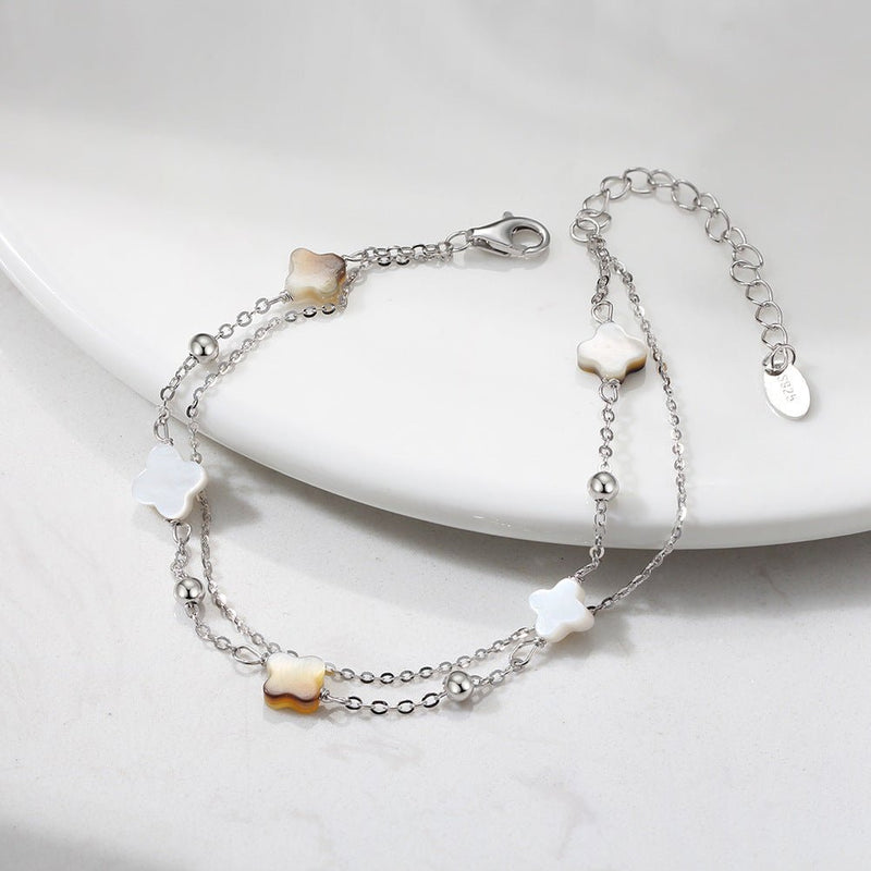 Bracelet double chaîne en argent 925 avec quatre trèfles en nacre blanche et noire délicate.