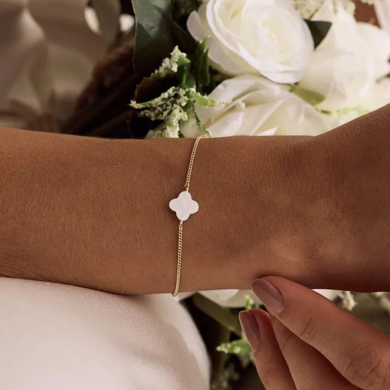 Bracelet doré fin avec pendentif trèfle blanc en pierre naturelle, ajustable et délicat.