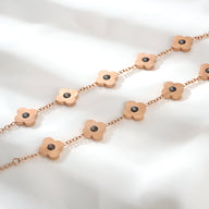 Bracelet femme en titane doré avec pendentifs trèfles magnétiques et centre rond noir.