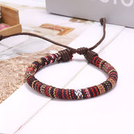 Bracelet tressé en coton aux motifs rouges, noirs et blancs avec fermoir ajustable en corde marron.