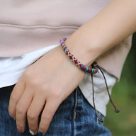 Bracelet tressé en coton multicolore avec fermoir coulissant porté au poignet.