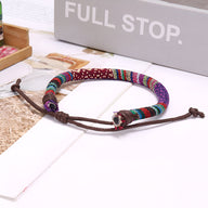 Bracelet tressé en coton multicolore avec motifs géométriques, fermoir ajustable en corde marron.
