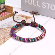 Bracelet tressé en coton multicolore à motifs géométriques avec fermeture coulissante en corde marron.