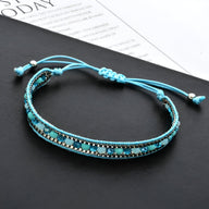 Bracelet tressé turquoise avec perles de riz noires et argentées, fermoir coulissant réglable.
