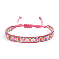 Bracelet tressé rose avec perles blanches et rouges, fermeture ajustable à nœud coulissant.