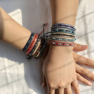 Bracelets tressés colorés avec perles de riz intégrées, style bohème sur poignets féminins, tons variés.