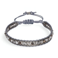 Bracelet tressé gris avec perles de riz argentées, fermeture réglable par nœud coulissant.