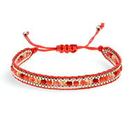 Bracelet tressé rouge avec perles de riz dorées et argentées, fermoir coulissant ajustable.