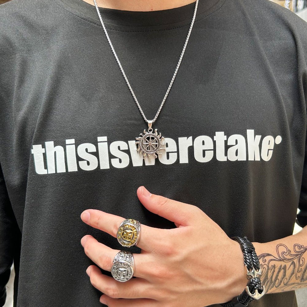 Bracelet tressé noir avec ancre métallique argentée porté au poignet.