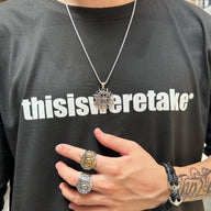 Bracelet tressé noir avec ancre métallique argentée porté au poignet.