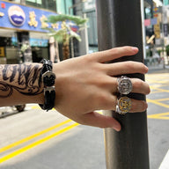 Bracelet tressé noir avec ancre métallique porté au poignet masculin tatoué, en ville.