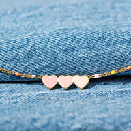 Bracelet en argent sterling avec trois cœurs roses et blancs sur chaîne fine dorée.