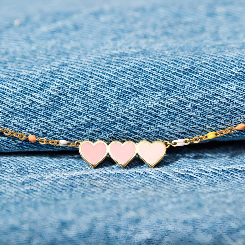 Bracelet en argent sterling avec trois cœurs roses et blancs sur chaîne fine dorée.