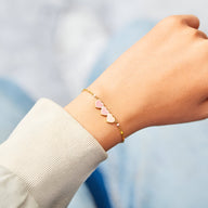 Bracelet fin en or avec trois petits cœurs roses en émail, style délicat féminin.