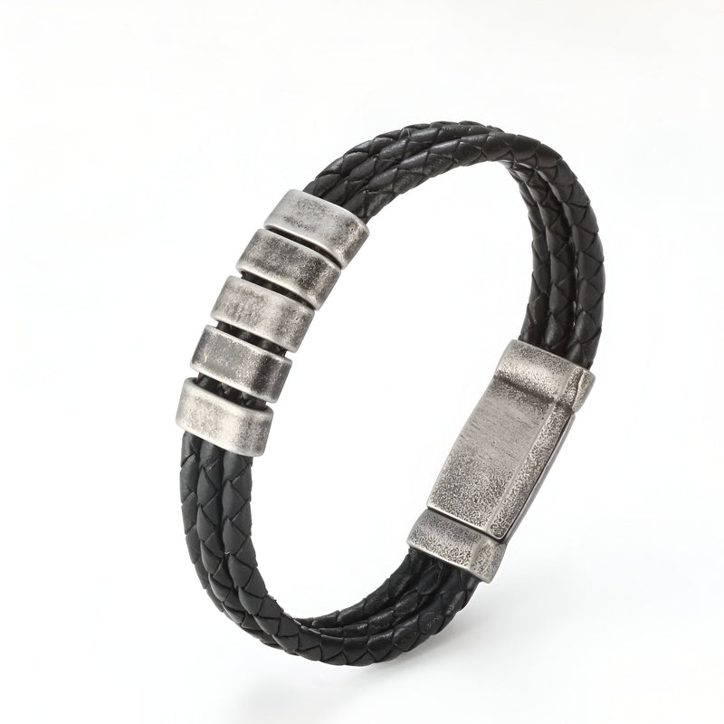 Bracelet triple cordon cuir noir tressé avec trois plaques métalliques argentées et fermoir aimanté.