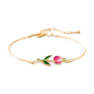 Bracelet en cuivre doré avec pendentif tulipe rose et feuille verte délicate.