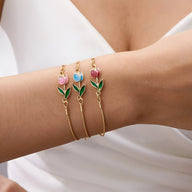 Bracelets en cuivre doré avec pendentifs tulipes rose clair, bleu et rose vif, feuilles vertes.