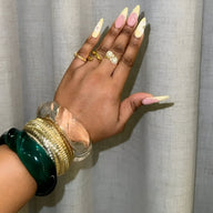 Bracelet large en acrylique transparent avec bracelets dorés et verts assortis sur poignet féminin.