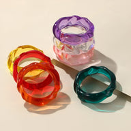 Bracelets unicolores en acrylique aux textures ondulées, couleurs rouge transparent, orange, violet, rose clair et vert.