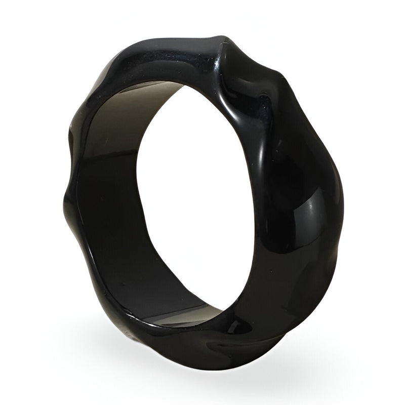 Bracelet rigide en acrylique noir avec surface ondulée et finition brillante.