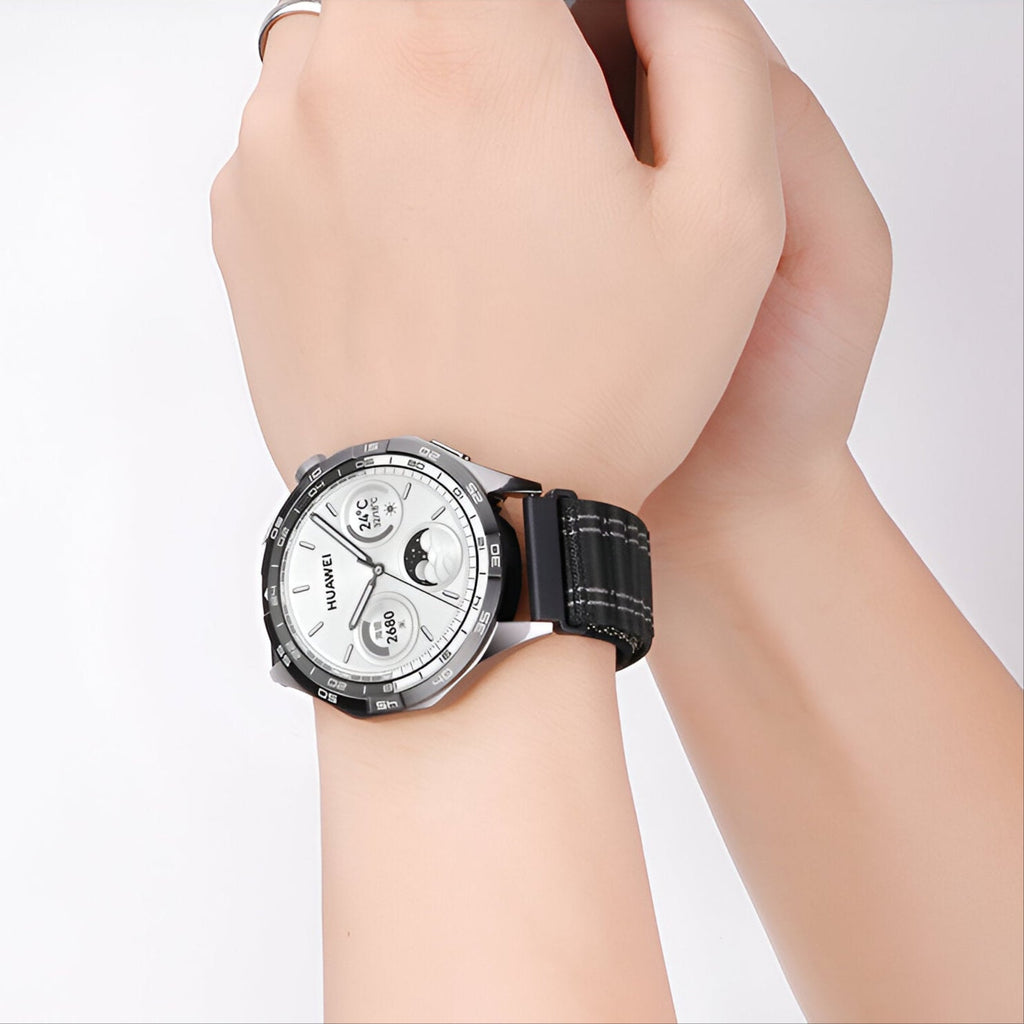 Montre Huawei avec bracelet velcro en nylon noir à lignes blanches, portée au poignet.