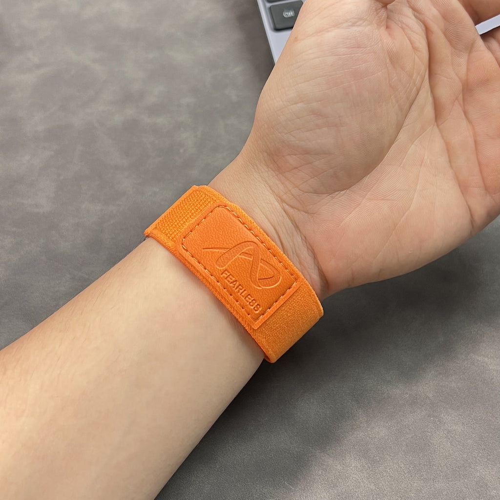 Bracelet velcro orange en nylon ultra léger et ajustable pour Apple Watch porté au poignet.