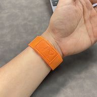 Bracelet velcro orange en nylon ultra léger et ajustable pour Apple Watch porté au poignet.