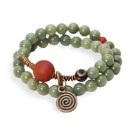 Bracelet double tour en graines de Bodhi vertes avec perles d'agate orange et pendentif spirale en métal bronze.
