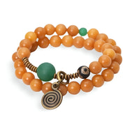 Bracelet féminin triple tour en graines de Bodhi orange et perles vertes avec pendentif spirale bronze.