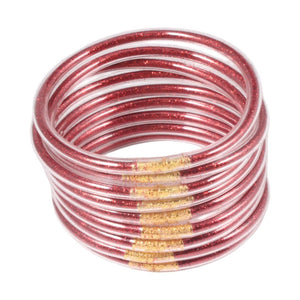 Ensemble de neuf joncs empilables en silicone souple rose translucide avec brillance dorée, design minimaliste et chic.