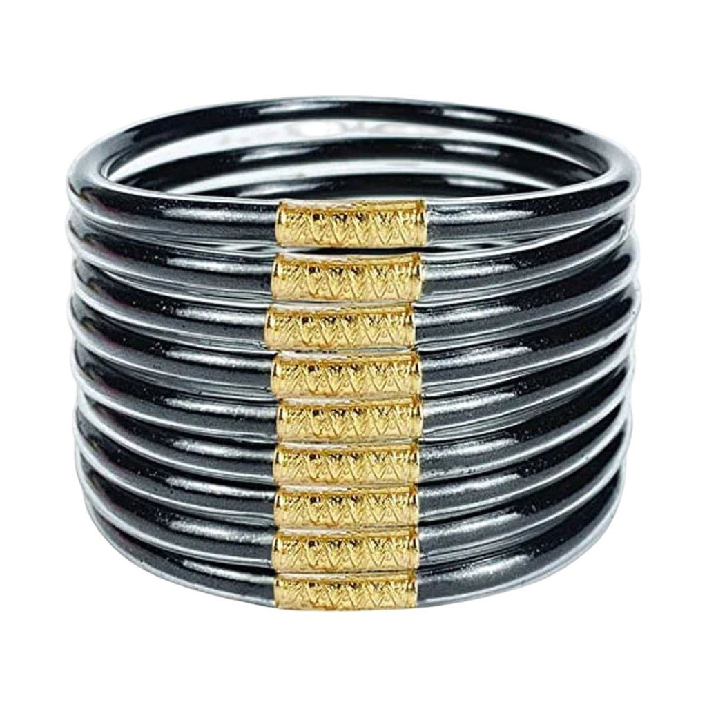 Lot de neuf bracelets joncs empilables en silicone noir avec ornements dorés texturés au centre, design minimaliste et chic.