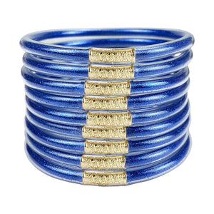 Lot de neuf bracelets joncs empilables en silicone bleu métallique avec détails dorés texturés.