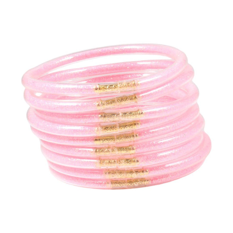 Ensemble de neuf bracelets joncs empilables en silicone souple rose pâle avec détails dorés brillants, design minimaliste et