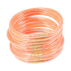 Lot de neuf bracelets joncs empilables en silicone souple coloris rose saumon avec dorure brillante et finition lisse.