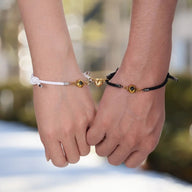 Bracelets cordons tressés noir et blanc avec cœur magnétique plaqué or et petites boules dorées.