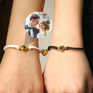 Bracelets couple en cordons tressés noir et blanc avec cœur magnétique plaqué or au centre.