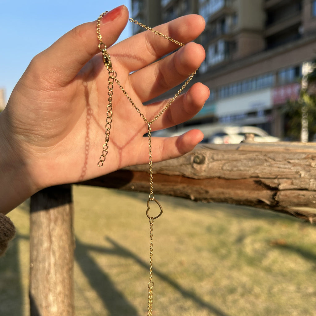 Bijou de main en acier inoxydable doré avec cœur central et chaîne fine élégante.