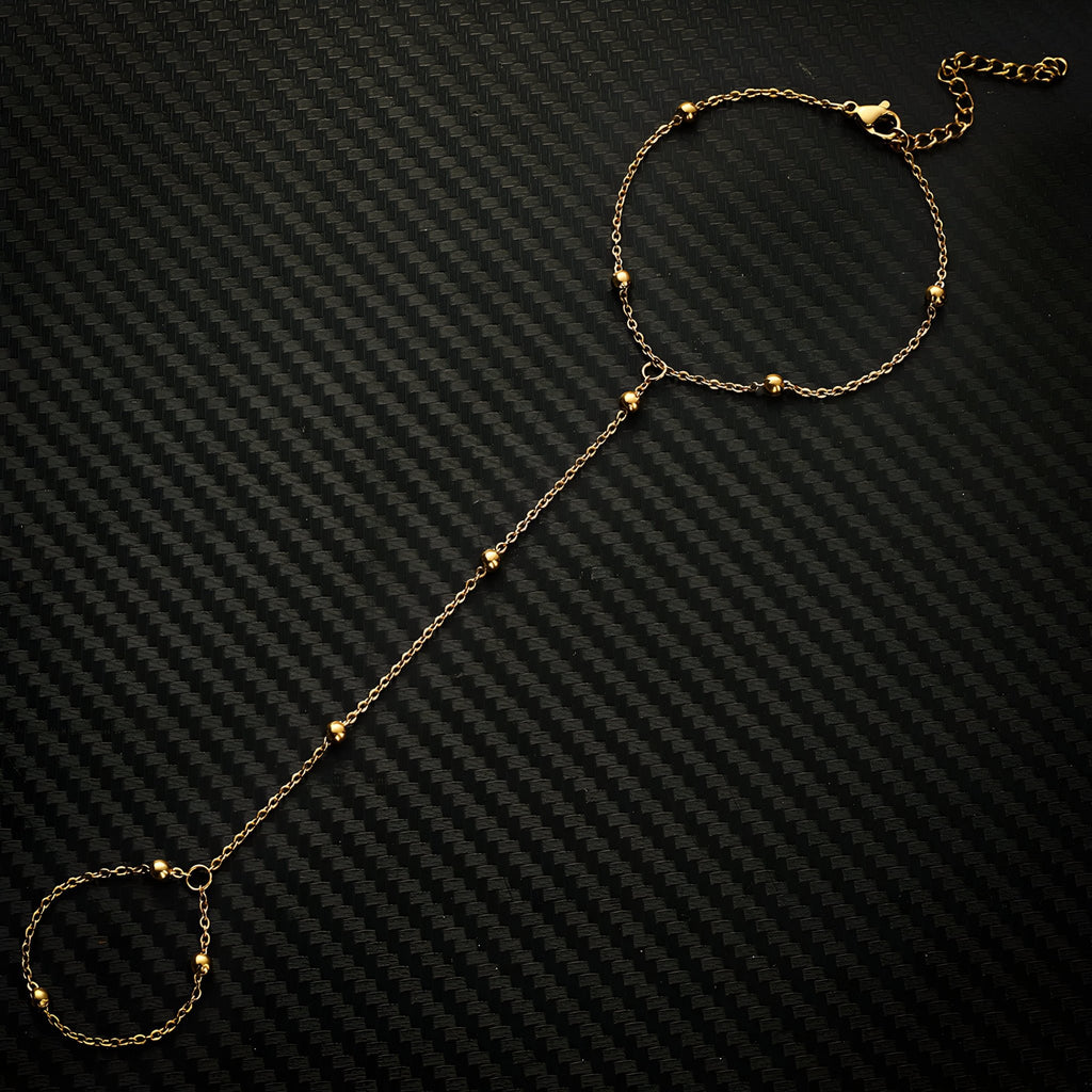 Bracelet de main en acier inoxydable doré avec perles fines et chaîne élégante.