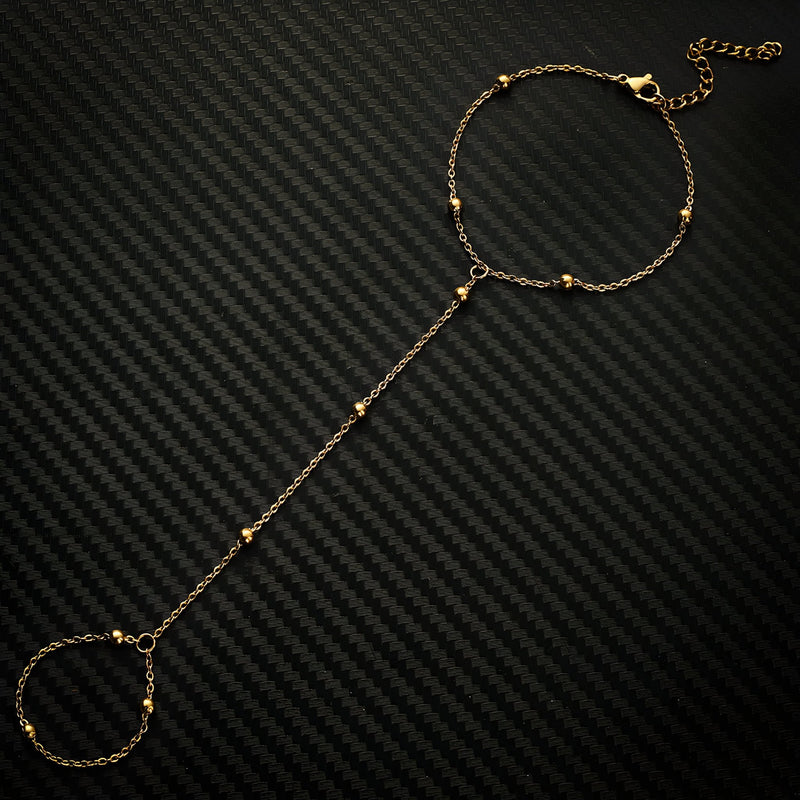 Bracelet de main en acier inoxydable doré avec perles fines et chaîne élégante.