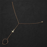 Bracelet de main chaîne fine en acier inoxydable doré avec croix chrétienne moderne.