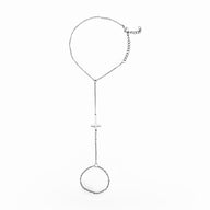Bracelet de main en acier inoxydable argenté avec chaîne fine et croix centrale minimaliste.