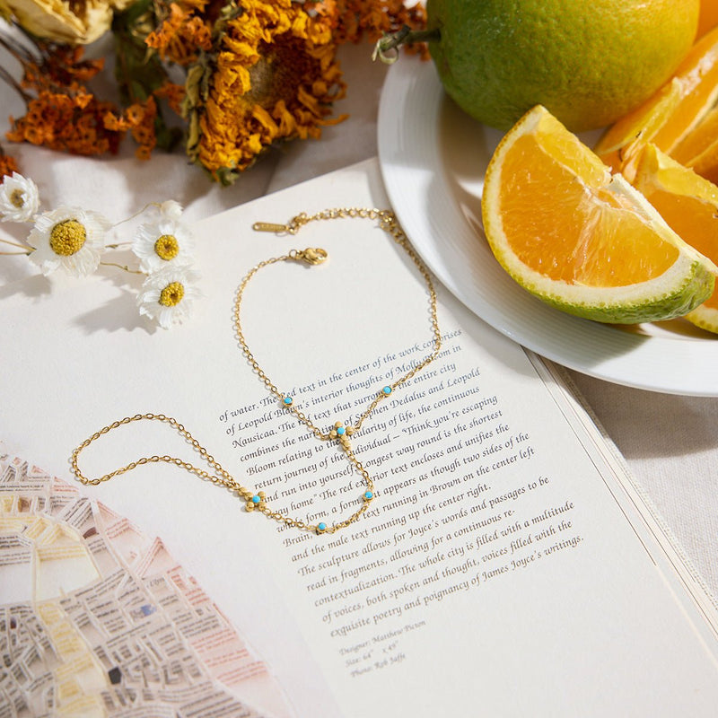 Chaîne de doigt dorée en acier inoxydable avec perles turquoise et petite croix chrétienne délicate.