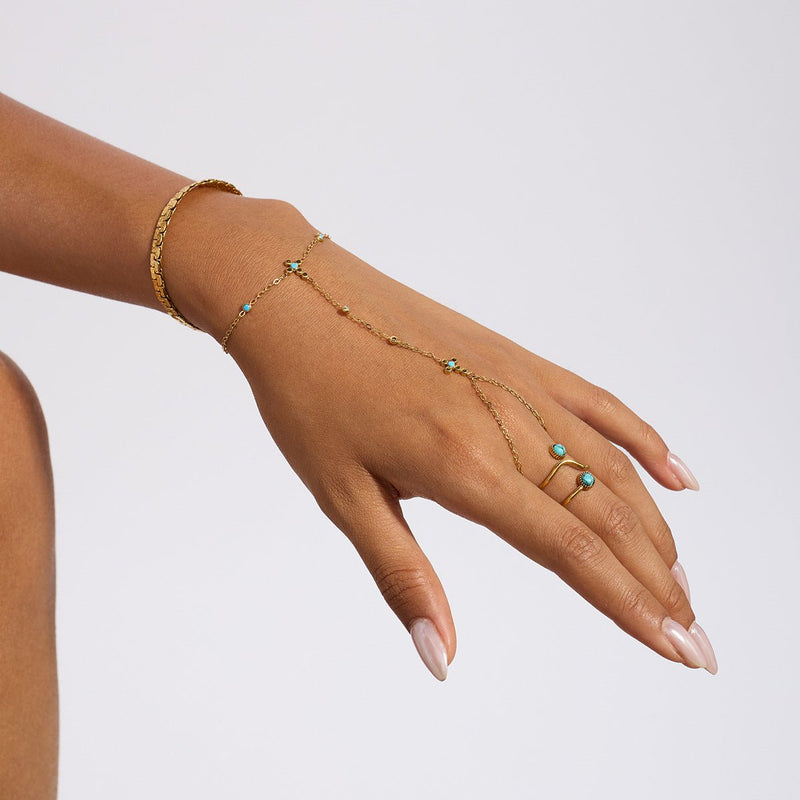 Chaîne de doigt dorée en acier inoxydable avec perles turquoise et petite croix chrétienne délicate.